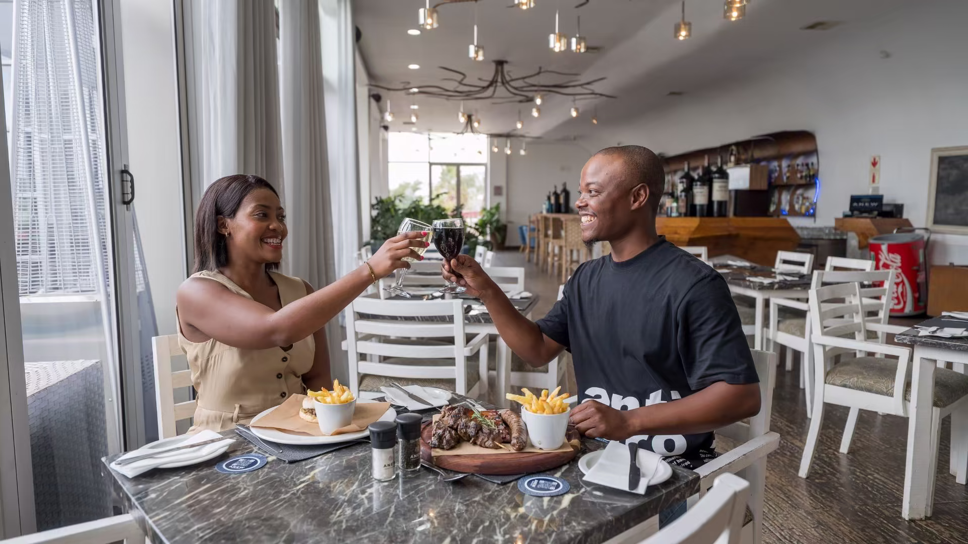 Couple toasting over a meaty platter inside